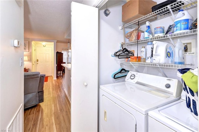 clothes washing area featuring independent washer and dryer, a textured ceiling, and light hardwood / wood-style floors