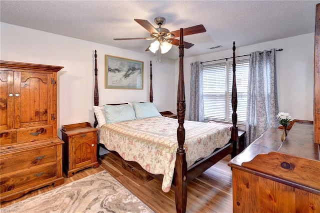 bedroom featuring hardwood / wood-style floors, ceiling fan, and a textured ceiling