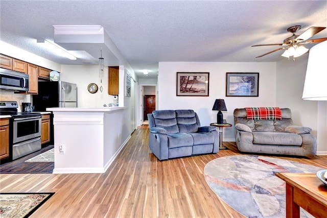 living room with a textured ceiling, light wood-type flooring, and ceiling fan