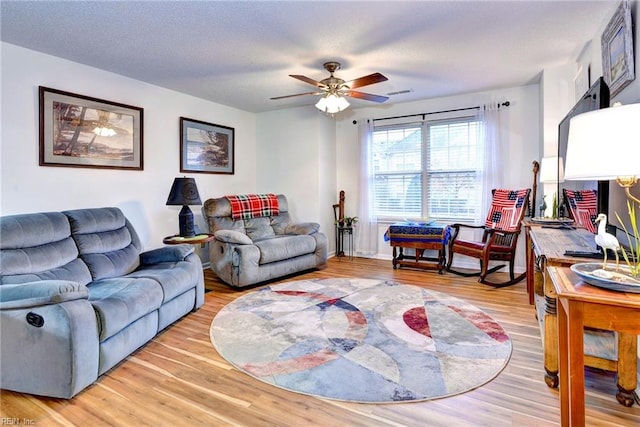 living room with ceiling fan, a textured ceiling, and hardwood / wood-style flooring