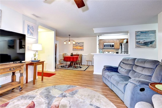 living room featuring ceiling fan, crown molding, and light hardwood / wood-style flooring