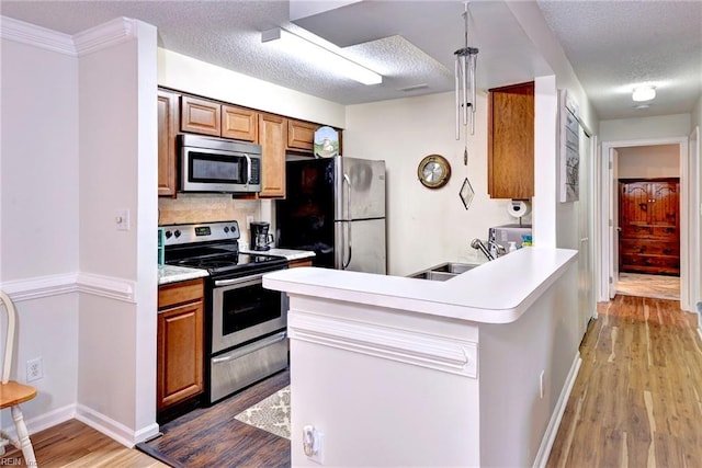 kitchen featuring sink, wood-type flooring, a textured ceiling, and appliances with stainless steel finishes