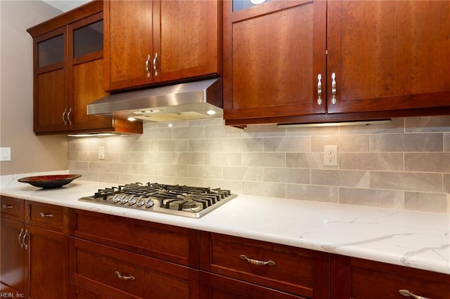 kitchen with tasteful backsplash, light stone countertops, and stainless steel gas cooktop