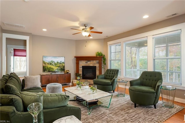 living room featuring a wealth of natural light, a fireplace, ceiling fan, and hardwood / wood-style floors