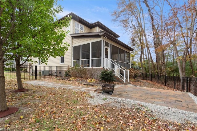 view of home's exterior featuring a sunroom and a fire pit