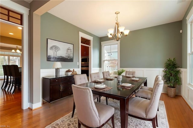 dining room with an inviting chandelier, a healthy amount of sunlight, and light wood-type flooring