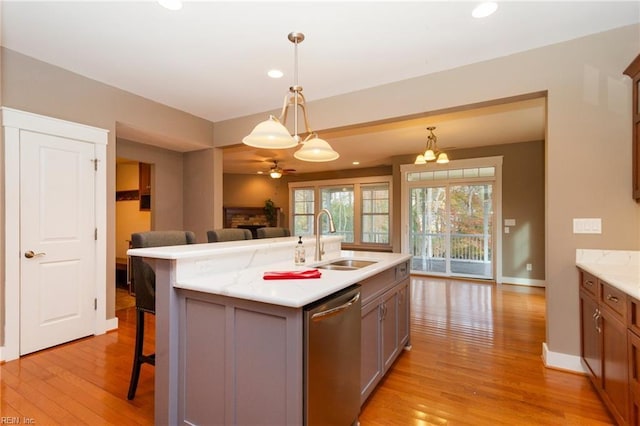 kitchen featuring stainless steel dishwasher, sink, a breakfast bar area, and light hardwood / wood-style flooring