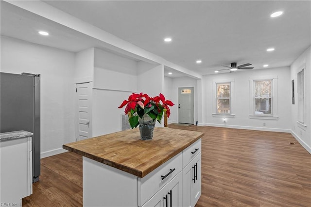 kitchen featuring wooden counters, dark hardwood / wood-style floors, stainless steel fridge, a kitchen island, and white cabinetry