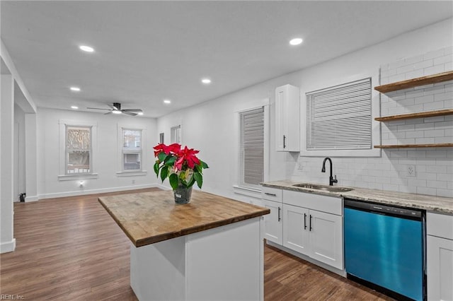 kitchen with white cabinetry, dishwasher, sink, light stone counters, and a kitchen island