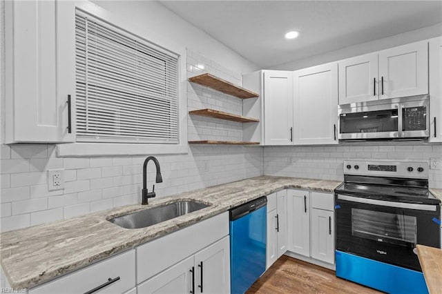 kitchen with appliances with stainless steel finishes, light stone counters, dark wood-type flooring, sink, and white cabinetry