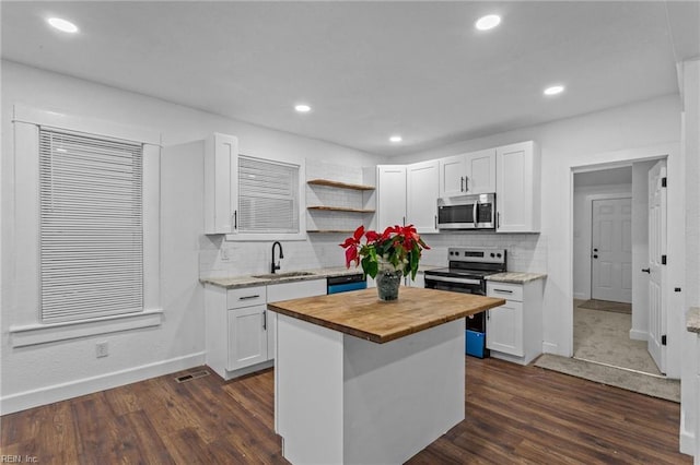 kitchen featuring a kitchen island, sink, white cabinetry, and stainless steel appliances