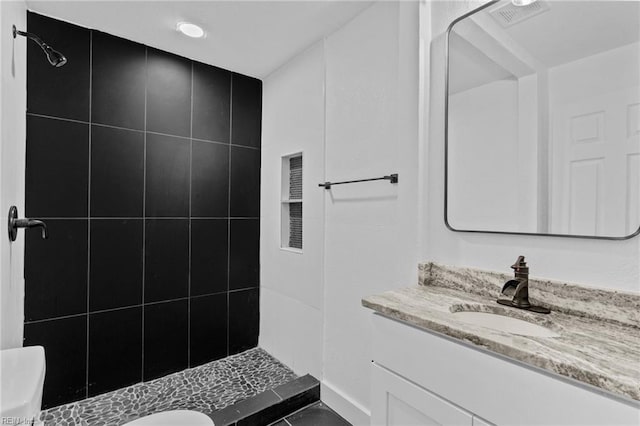 bathroom featuring vanity, toilet, and a tile shower