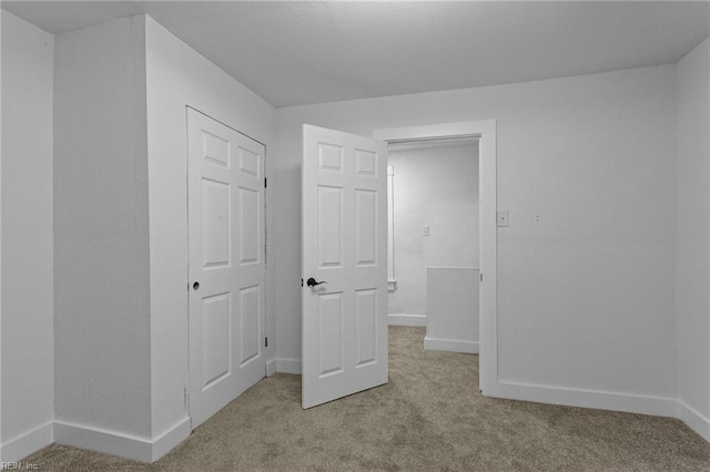 unfurnished bedroom featuring a closet and light colored carpet