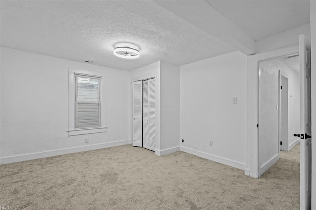 unfurnished bedroom with a textured ceiling, light colored carpet, and a closet