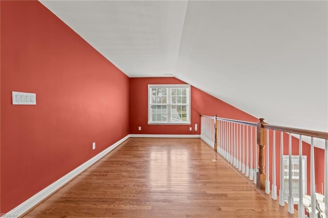 bonus room with hardwood / wood-style flooring and vaulted ceiling