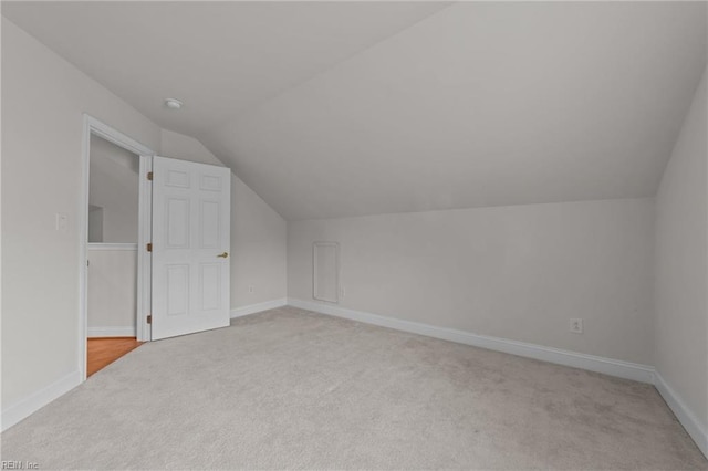 additional living space with light carpet and vaulted ceiling