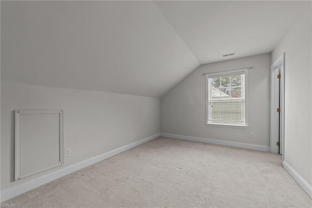 additional living space featuring light colored carpet and lofted ceiling