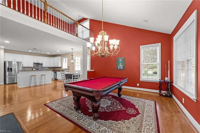 rec room with light wood-type flooring, an inviting chandelier, high vaulted ceiling, and billiards