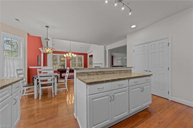 kitchen with white cabinetry, a center island, pendant lighting, and light wood-type flooring