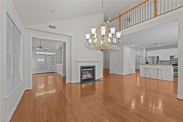 4756 Winterberry Ct, Williamsburg, VA 23188 - unfurnished living room with light wood-style flooring, a fireplace with flush hearth, a chandelier, ceiling fan, and a high ceiling