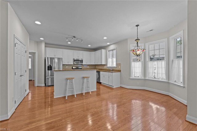 4756 Winterberry Ct, Williamsburg, VA 23188 - kitchen with appliances with stainless steel finishes, white cabinetry, light wood-style floors, a center island, and pendant lighting