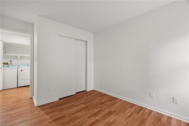 unfurnished bedroom with separate washer and dryer and light hardwood / wood-style floors