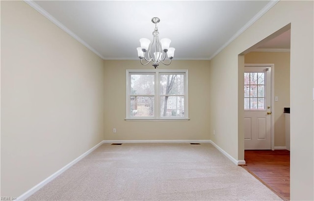 empty room with a wealth of natural light, crown molding, hardwood / wood-style floors, and a notable chandelier