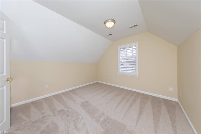 additional living space featuring light colored carpet and vaulted ceiling