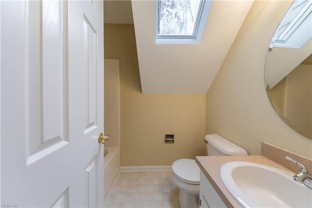 bathroom with a skylight, a bathtub, vanity, and toilet