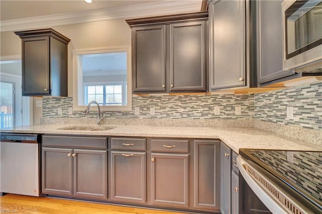 kitchen with light wood-type flooring, backsplash, ornamental molding, stainless steel appliances, and sink