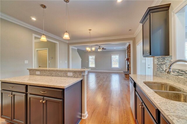 kitchen with light stone countertops, sink, light hardwood / wood-style floors, and ceiling fan with notable chandelier