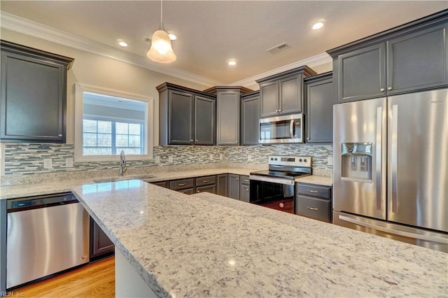 kitchen with light stone countertops, sink, hanging light fixtures, crown molding, and appliances with stainless steel finishes