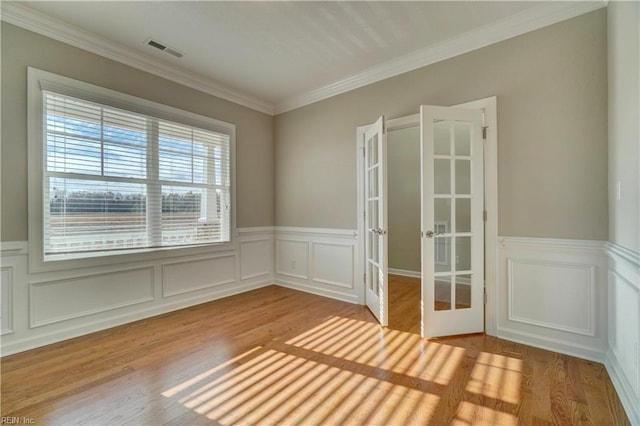 empty room with crown molding, french doors, and light hardwood / wood-style floors