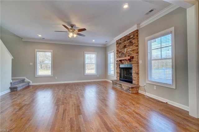 unfurnished living room featuring a fireplace, light wood-type flooring, ceiling fan, and a healthy amount of sunlight