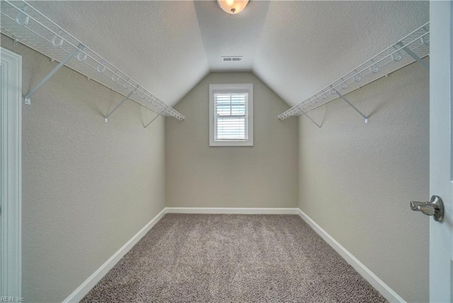 walk in closet with carpet and lofted ceiling