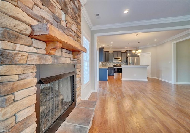 unfurnished living room with a stone fireplace, light hardwood / wood-style flooring, an inviting chandelier, and ornamental molding