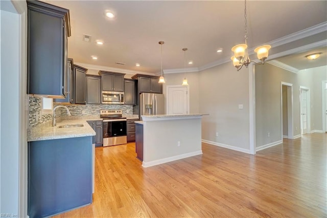 kitchen featuring appliances with stainless steel finishes, light wood-type flooring, sink, pendant lighting, and a kitchen island