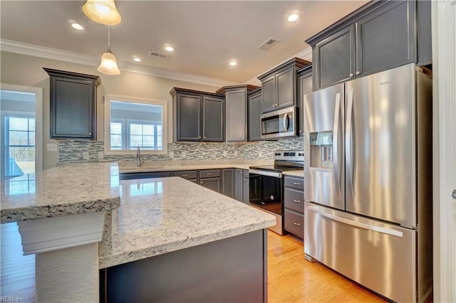 kitchen featuring backsplash, crown molding, hanging light fixtures, light hardwood / wood-style flooring, and stainless steel appliances