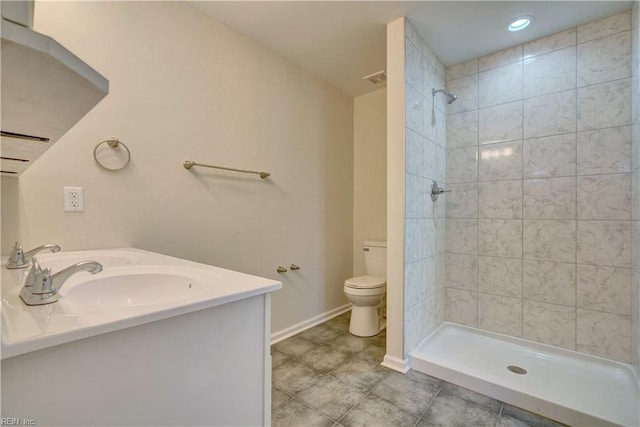 bathroom featuring toilet, tiled shower, and vanity