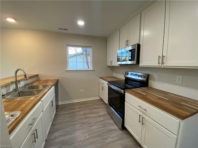 kitchen featuring white cabinets, sink, wood counters, and stainless steel appliances