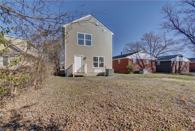 rear view of property with a lawn and central air condition unit