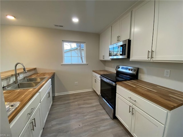 kitchen with white cabinets, wooden counters, sink, and stainless steel appliances