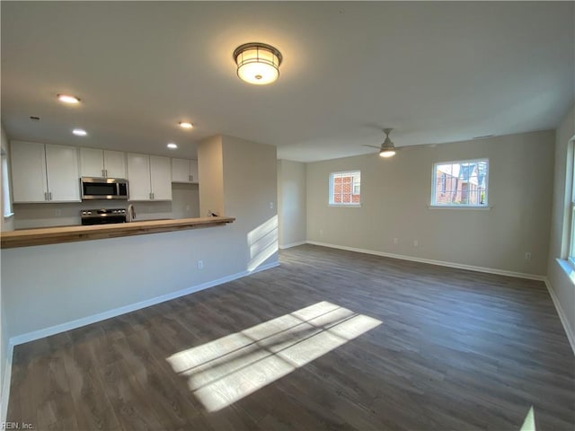 kitchen featuring ceiling fan, kitchen peninsula, white cabinetry, appliances with stainless steel finishes, and dark hardwood / wood-style flooring