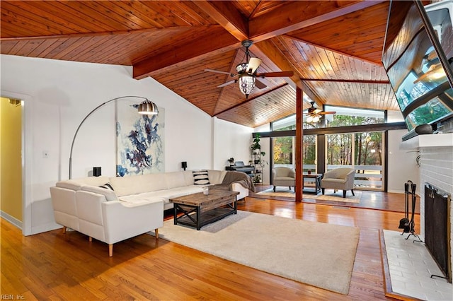 living room featuring vaulted ceiling with beams, ceiling fan, a fireplace, and light hardwood / wood-style flooring