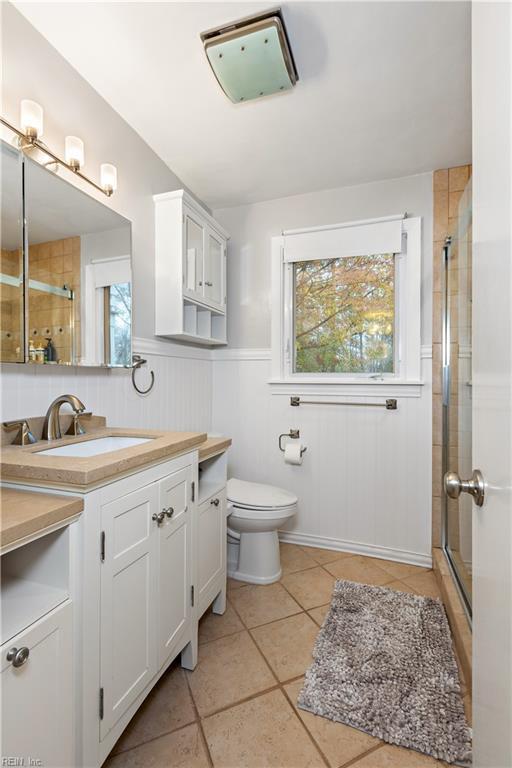 bathroom with tile patterned flooring, vanity, toilet, and walk in shower