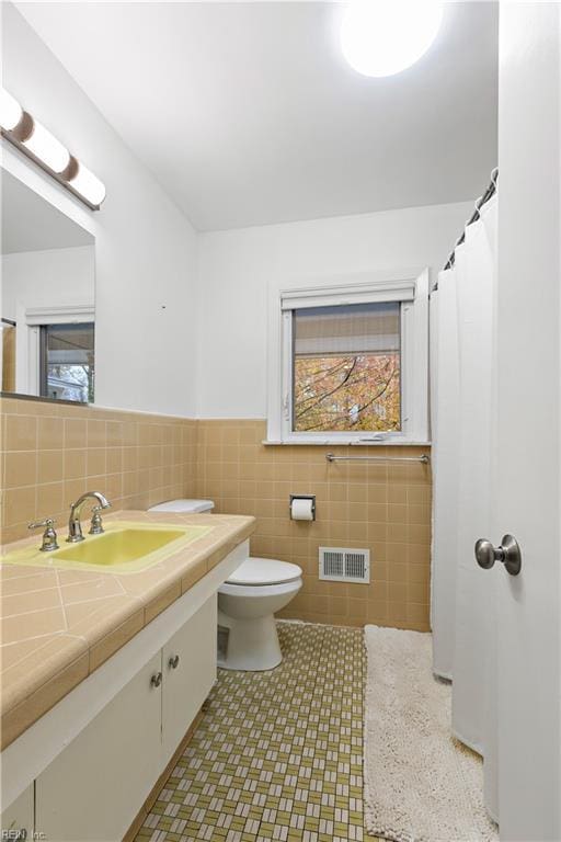 bathroom featuring vanity, toilet, and tile walls