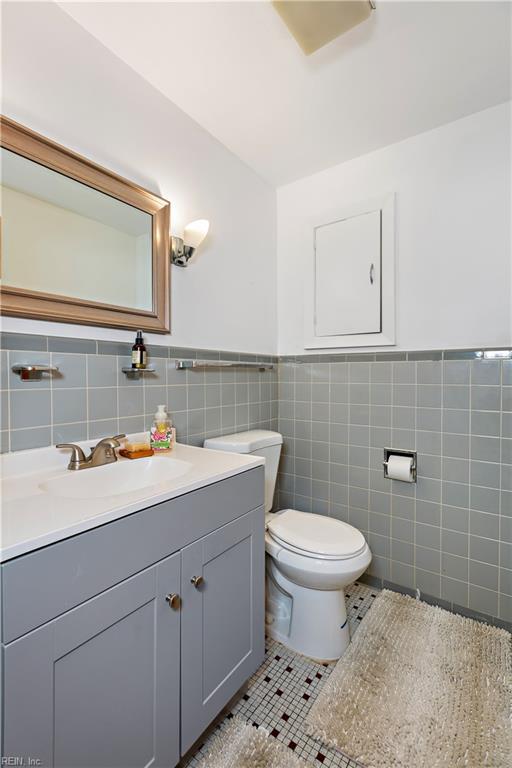 bathroom with tile patterned floors, vanity, toilet, and tile walls