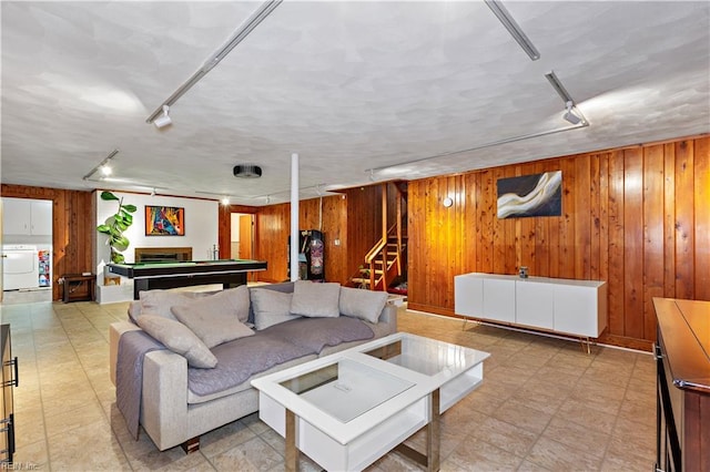 living room featuring wooden walls, pool table, and washer / dryer