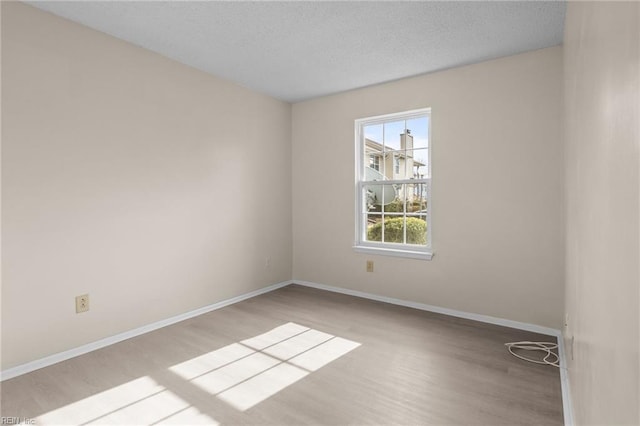 spare room featuring a textured ceiling and light wood-type flooring