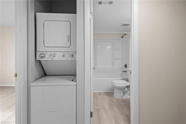 laundry room with stacked washer and dryer and light hardwood / wood-style floors